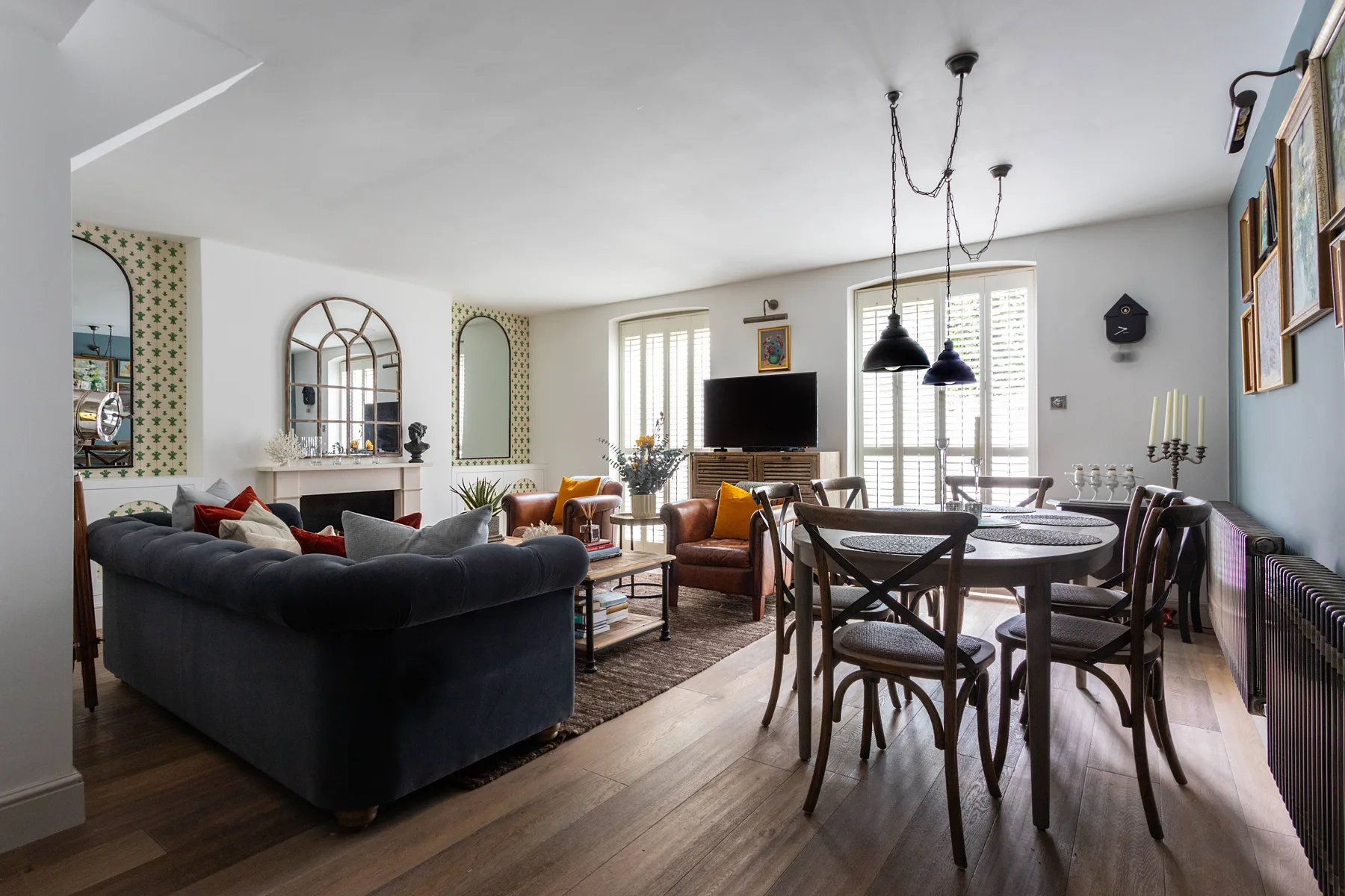 A living and dining room with seating, a dining table, and a television.