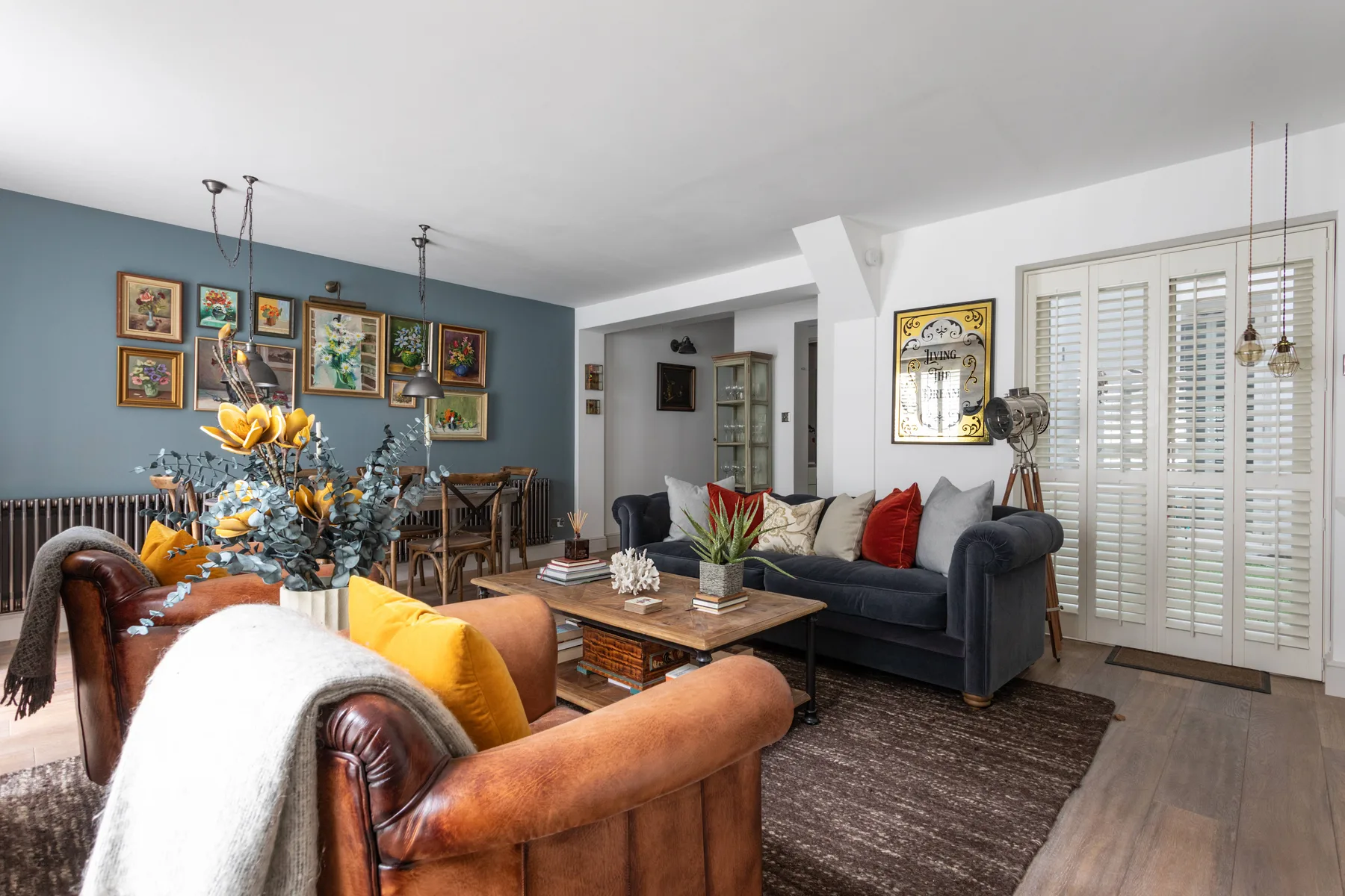 A living room with seating, a coffee table, and framed artwork on a blue wall.