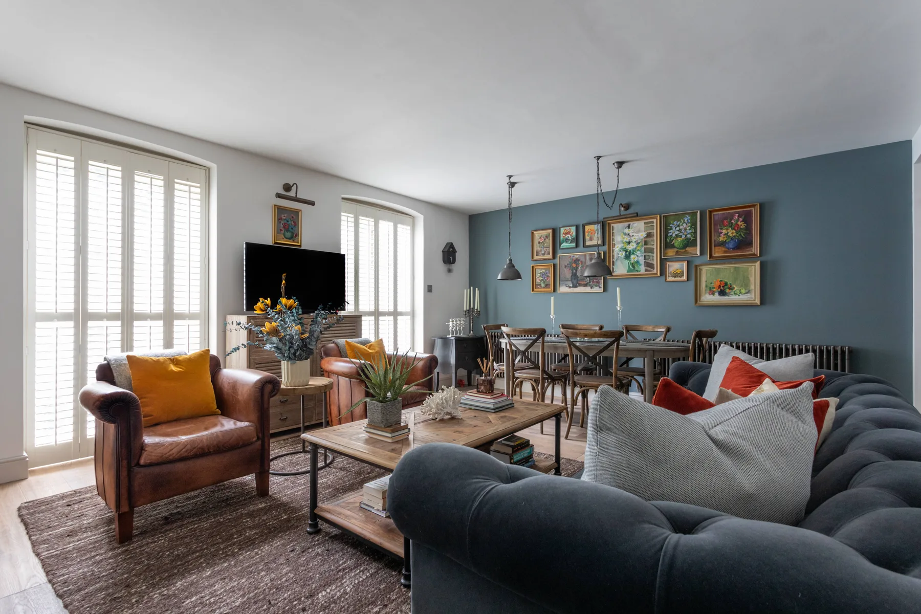 Living room with seating, a dining table, and framed artwork on the wall.