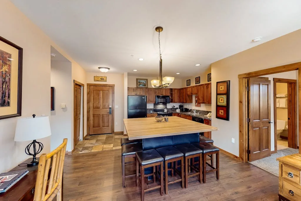 An open kitchen and dining area features a wooden island with seating.