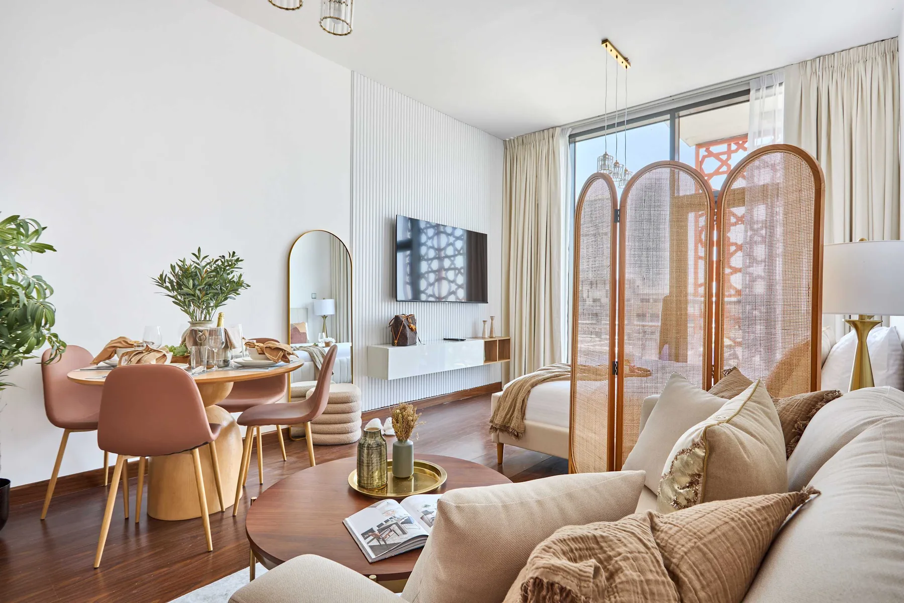 A bright living and dining area with seating, a dining table, and a television.