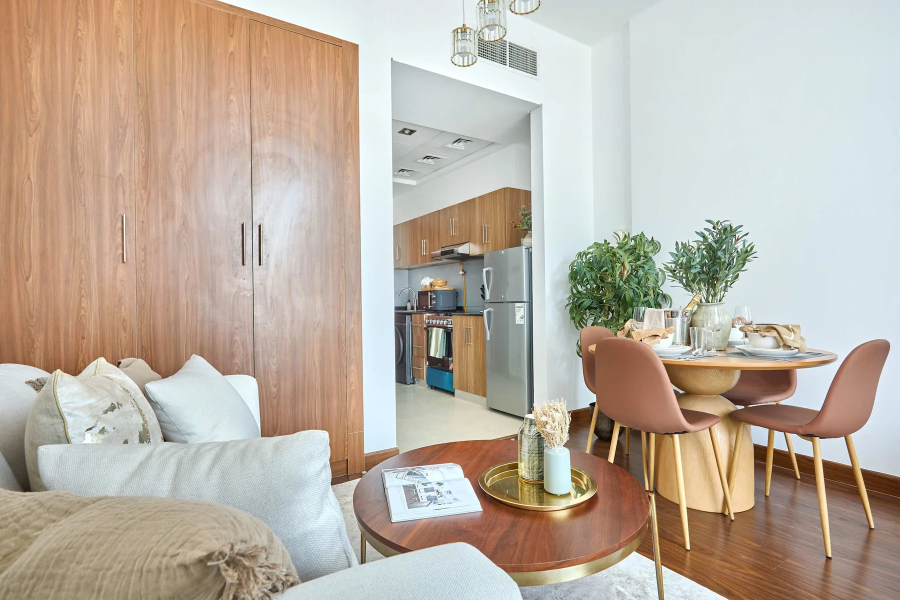 A bright living and dining area with a kitchen visible beyond the doorway.