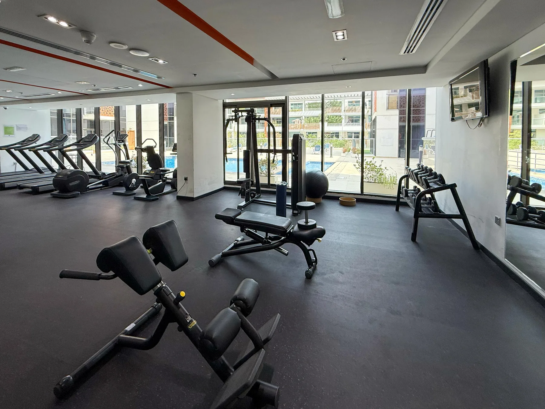 A gym with exercise machines and large windows.