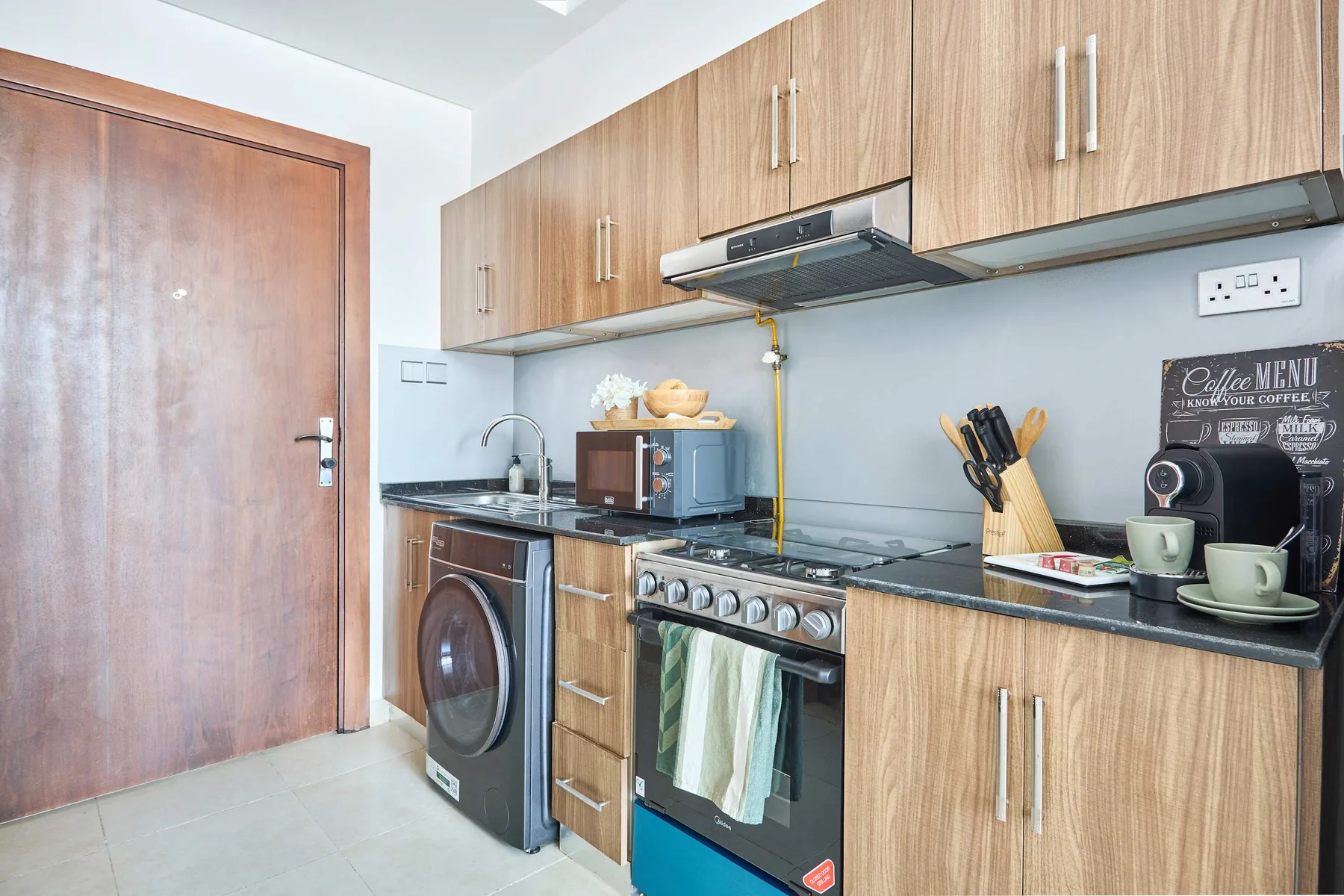 A compact kitchen with wood cabinets, a stove, and a washing machine.