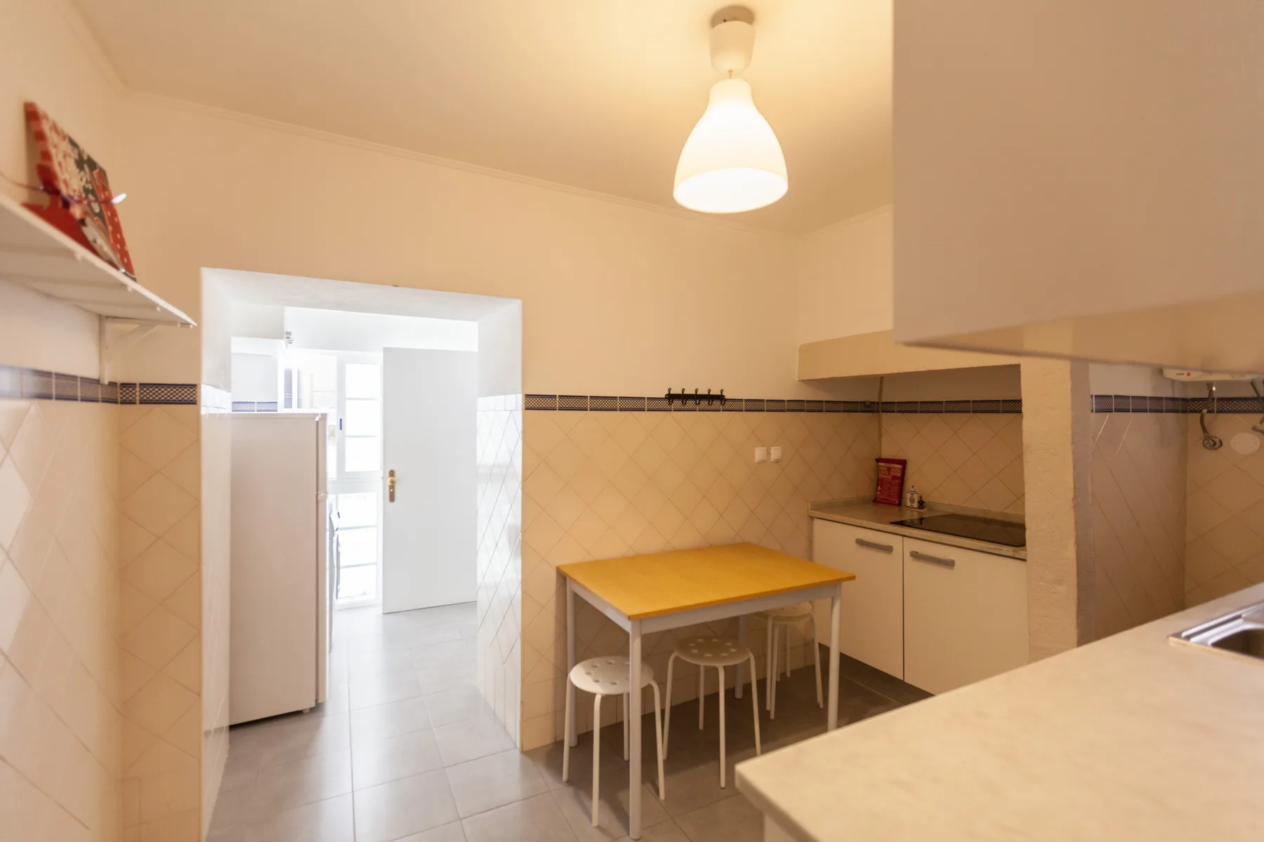 Una cocina con una mesa de comedor y una puerta hacia una habitación más luminosa.