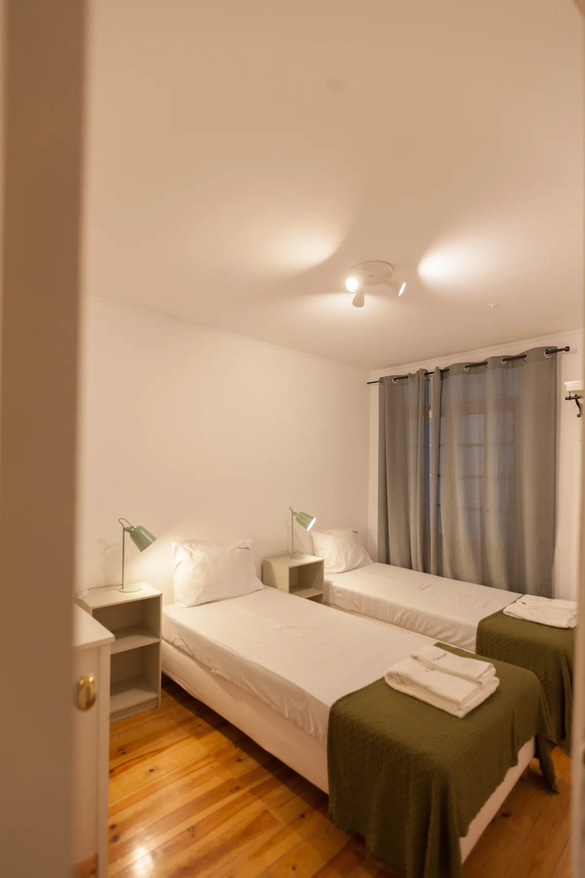 Un dormitorio con dos camas, mesillas y cortinas.