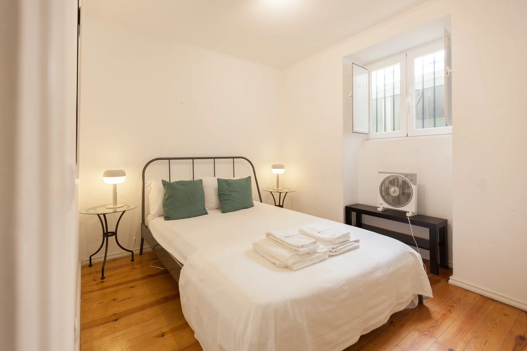 Un dormitorio luminoso con una cama bien tendida y toallas dobladas.