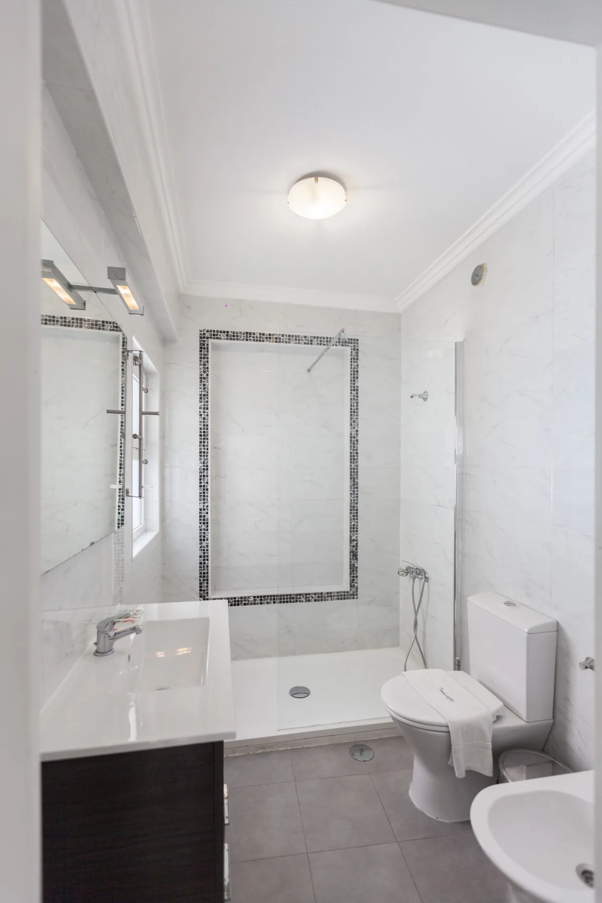 Un baño luminoso con ducha, lavabo e inodoro.