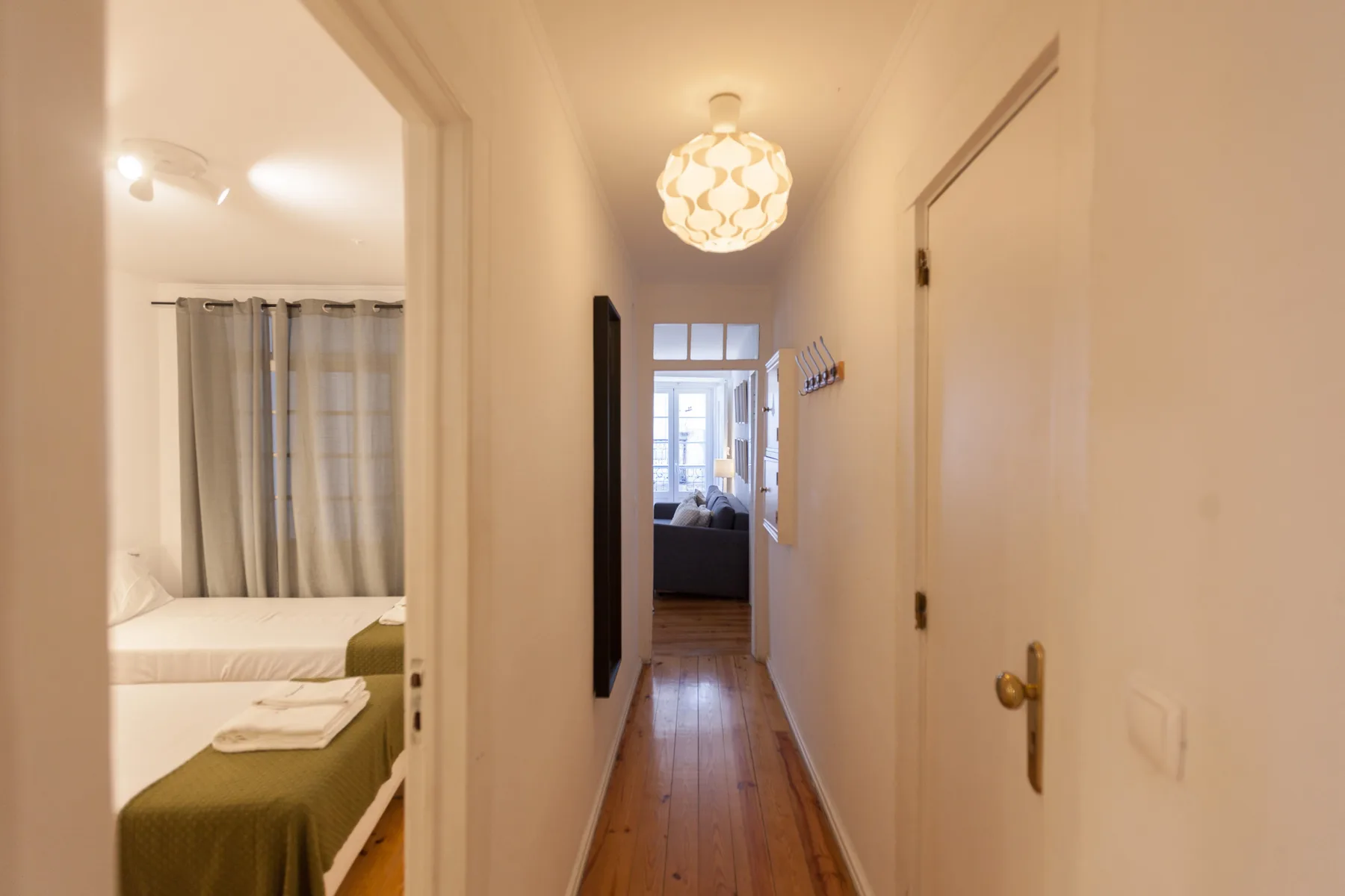 Un pasillo estrecho conduce junto a un dormitorio hacia una luminosa zona de estar.