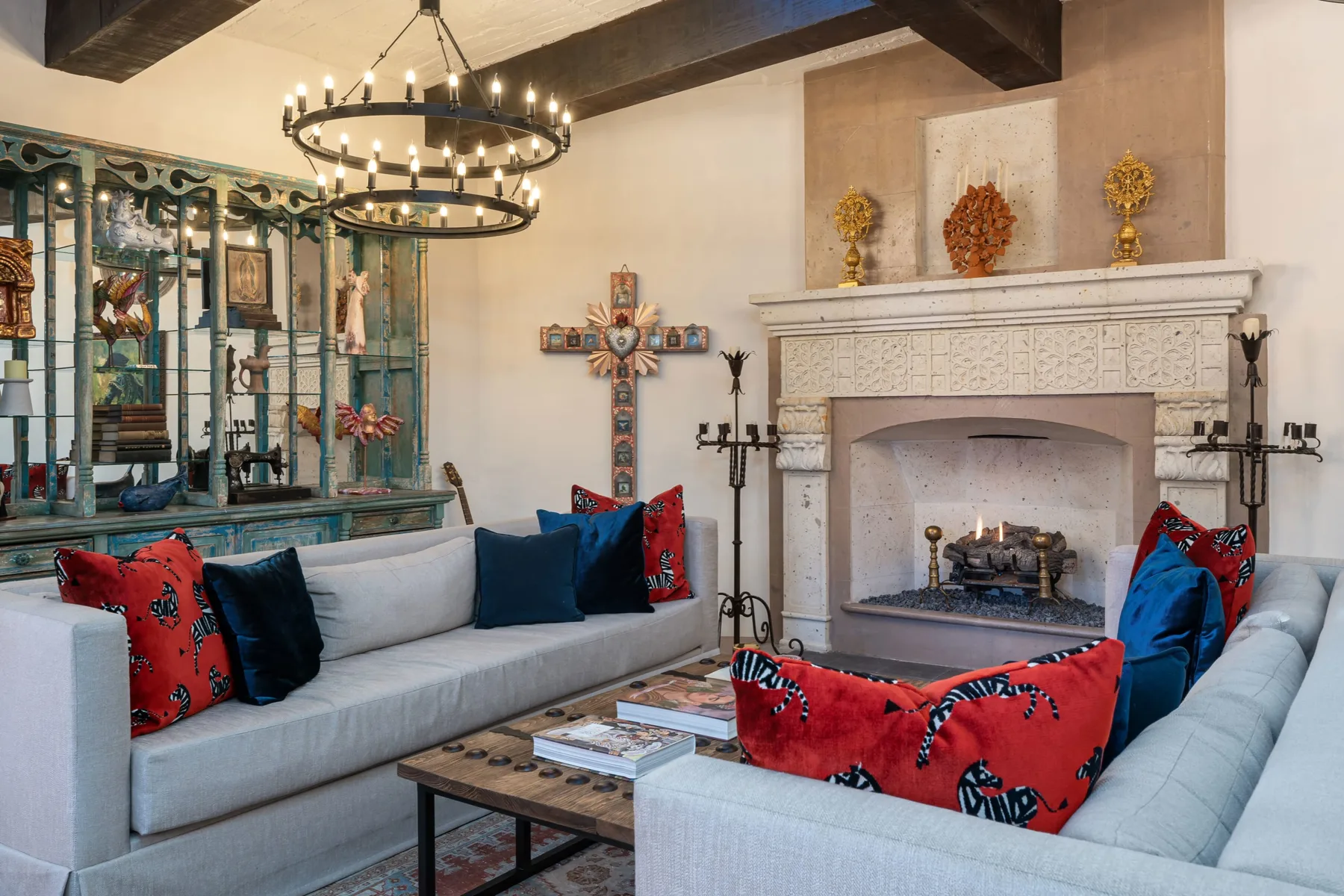 A living room with pale seating, colorful cushions, and a carved fireplace.