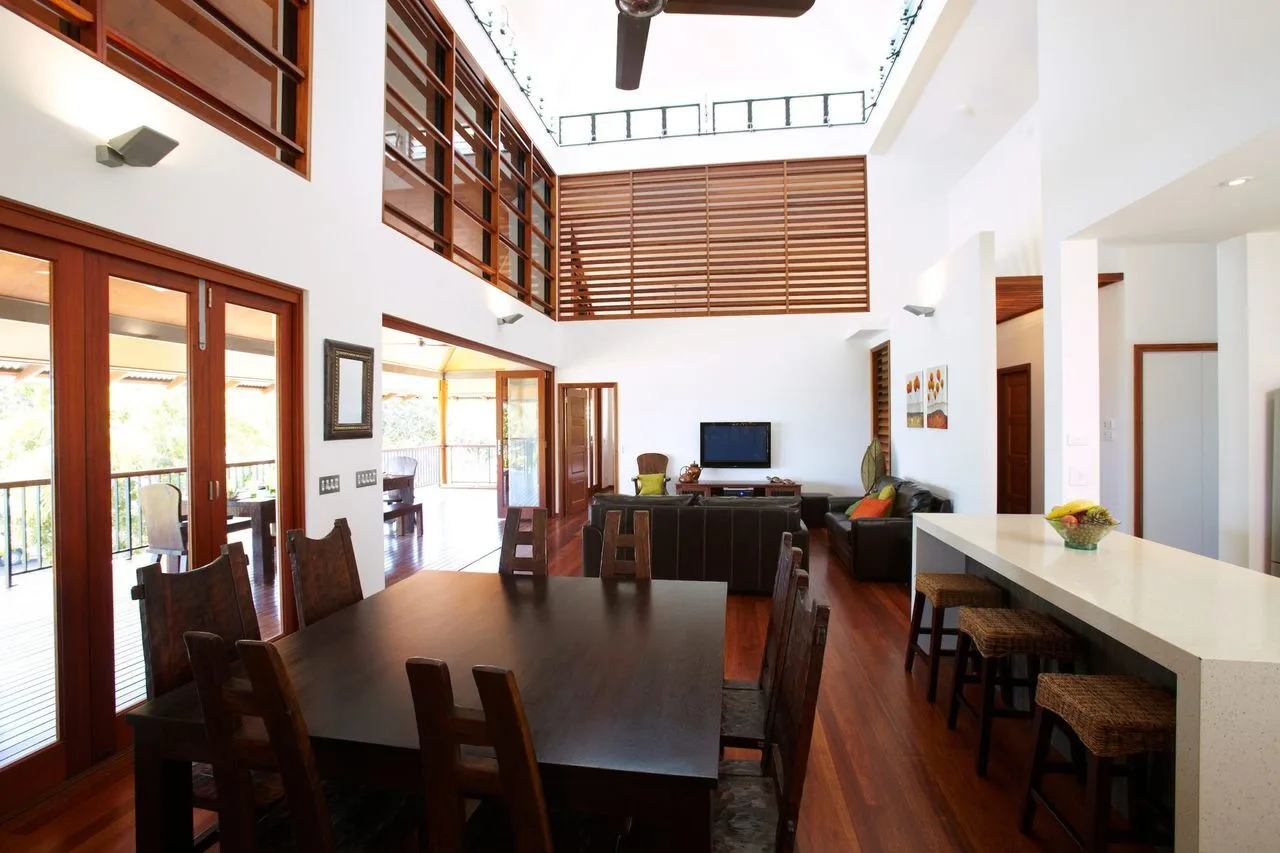 A bright open-plan dining area with a long table and kitchen counter.