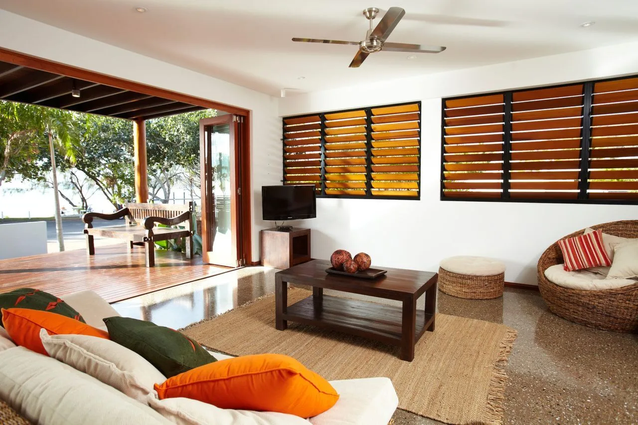 A living room with seating, a coffee table, and wooden window blinds.