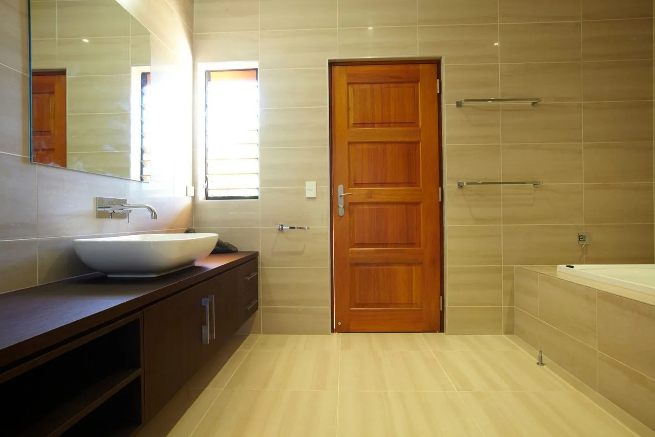 A tiled bathroom with a wooden door, sink, and bathtub.
