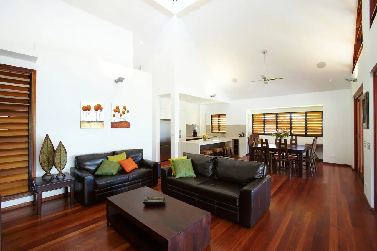 A living and dining area with dark seating, a coffee table, and wooden flooring.