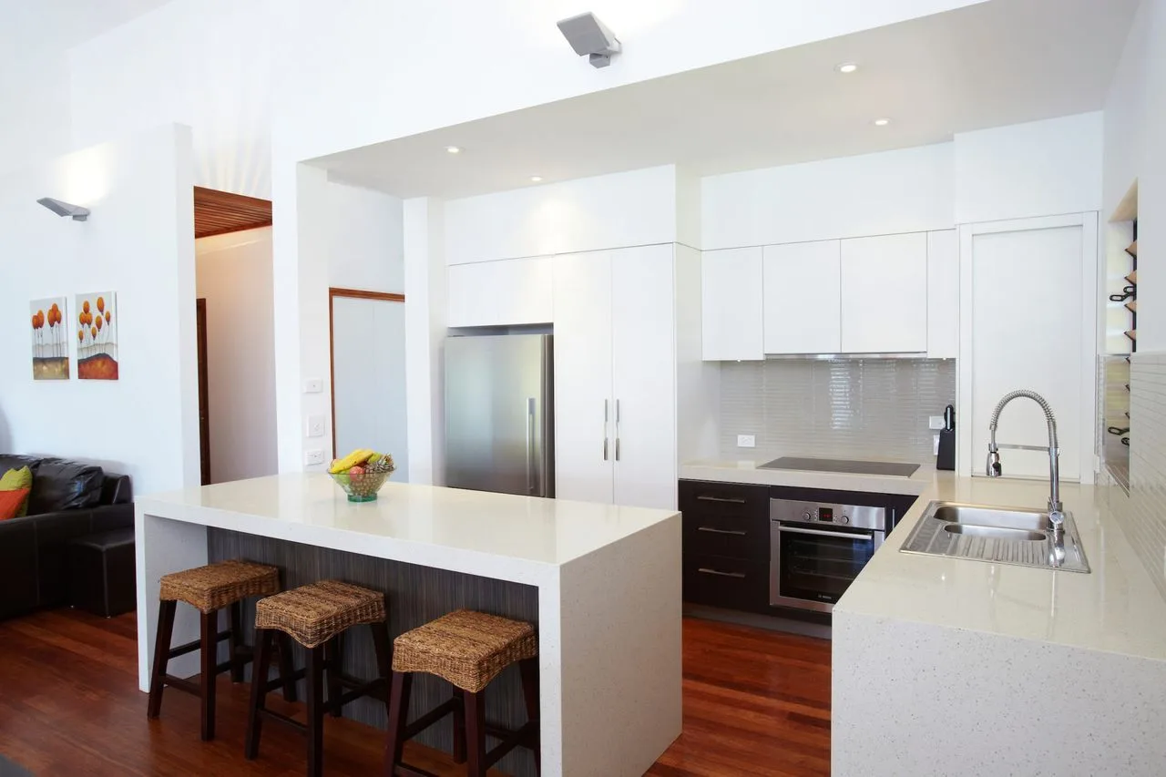 A bright modern kitchen with a central island and bar stools.
