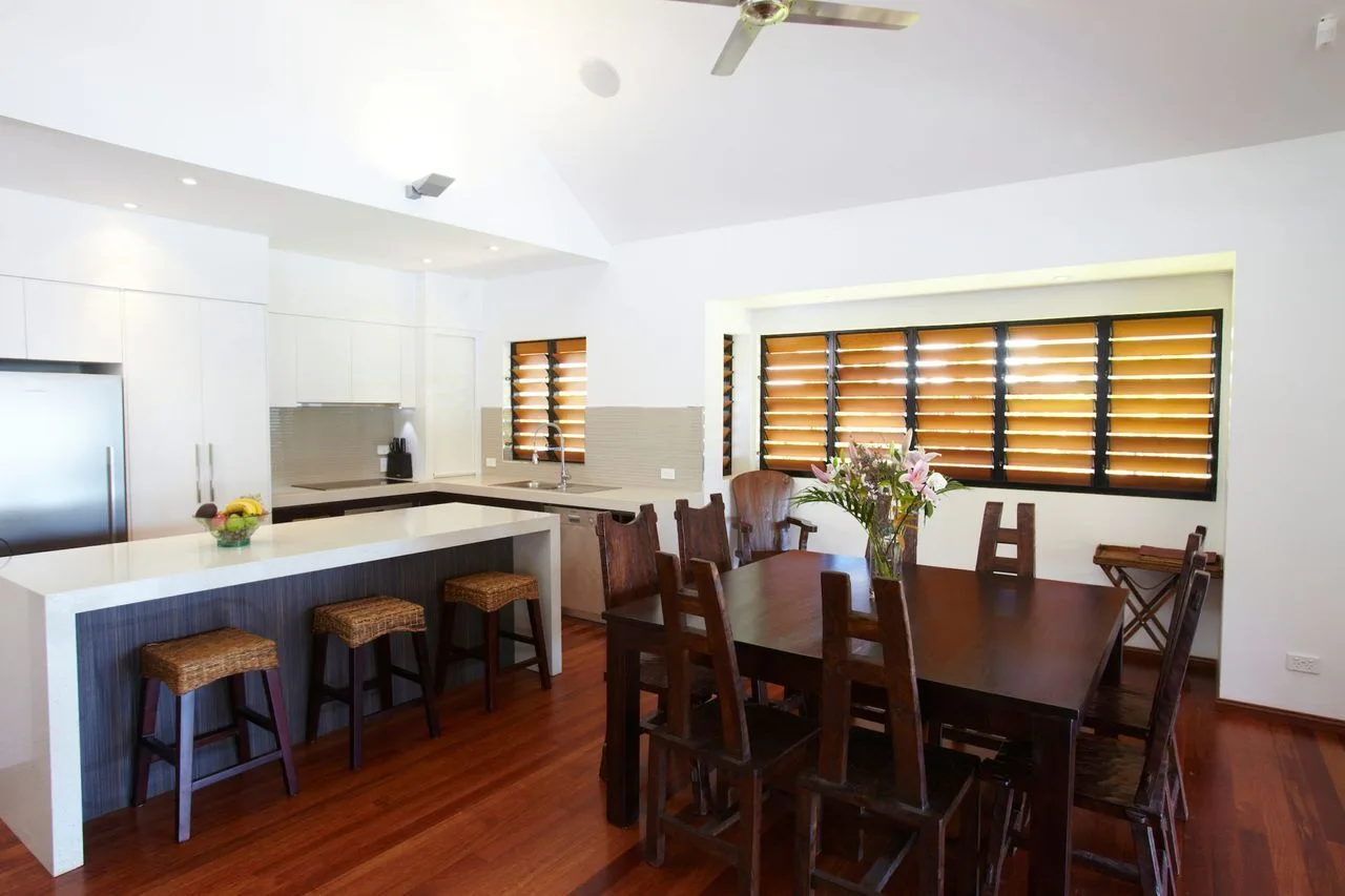 A dining area with a wooden table beside a bright kitchen.
