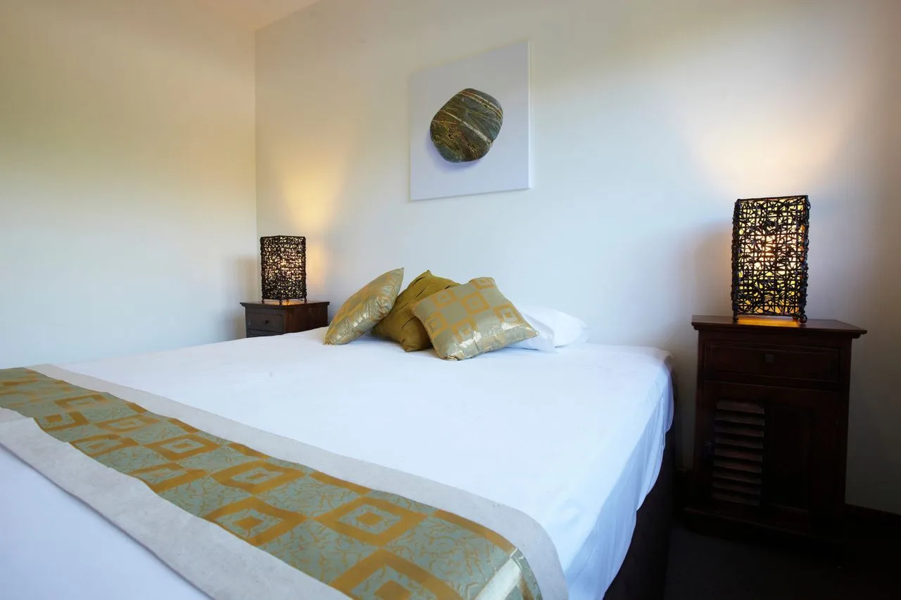 A bedroom with a neatly made bed and decorative pillows.