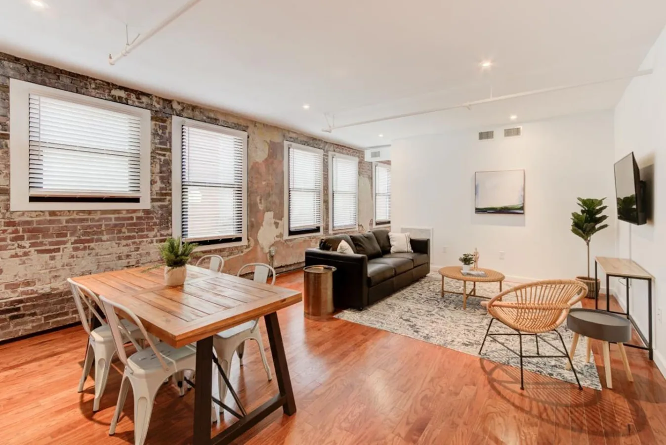 A bright living and dining area with exposed brick walls and wooden flooring.