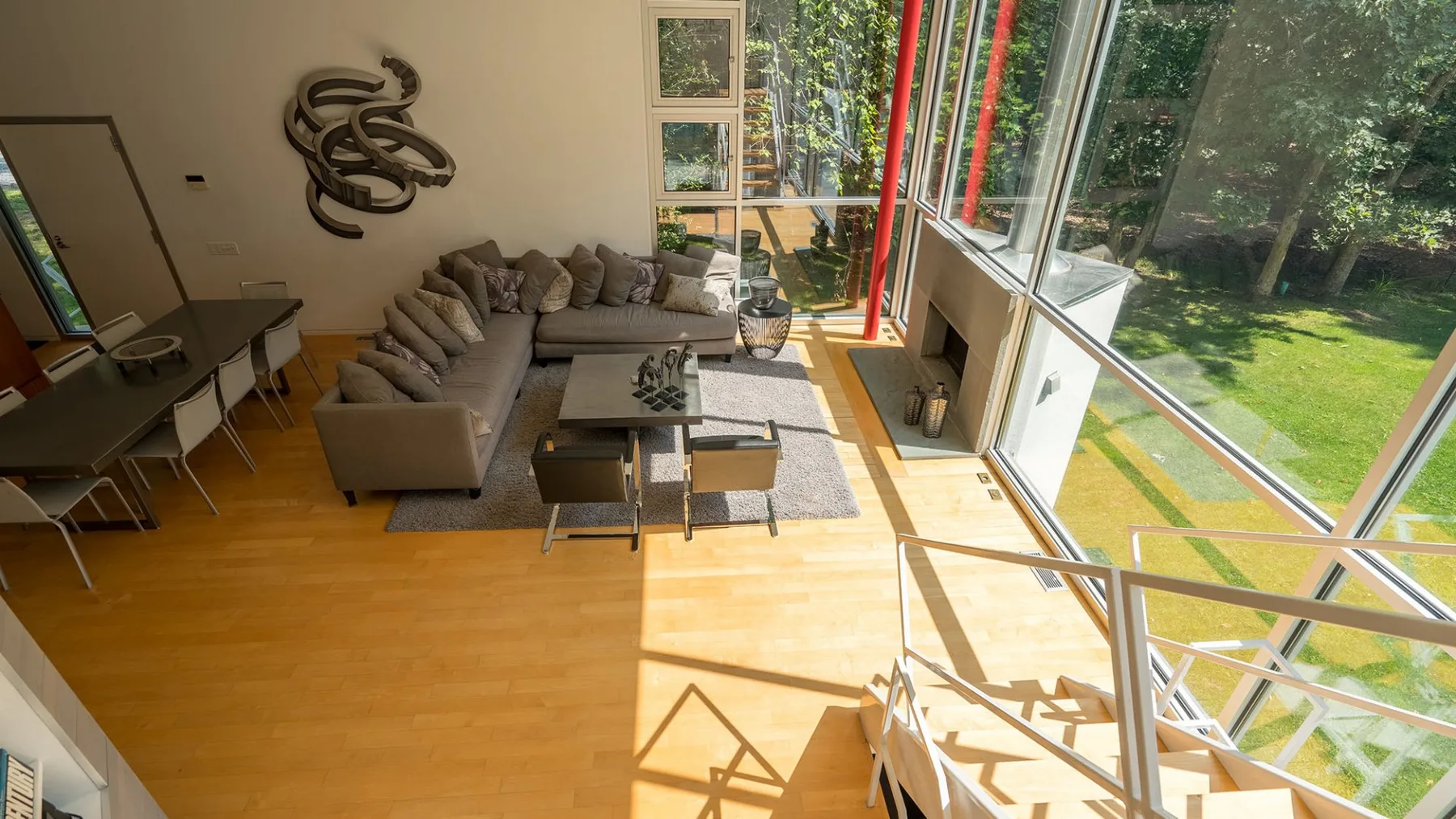 A sunlit living room with seating beside large windows overlooking a green garden.
