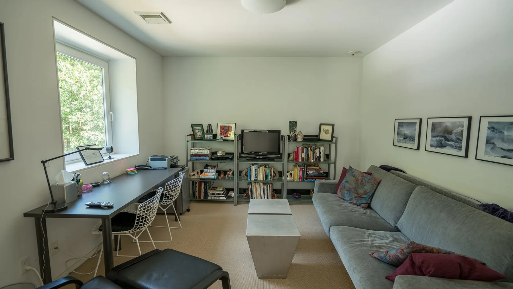 A living room with a sofa, coffee table, and desk beside a window.