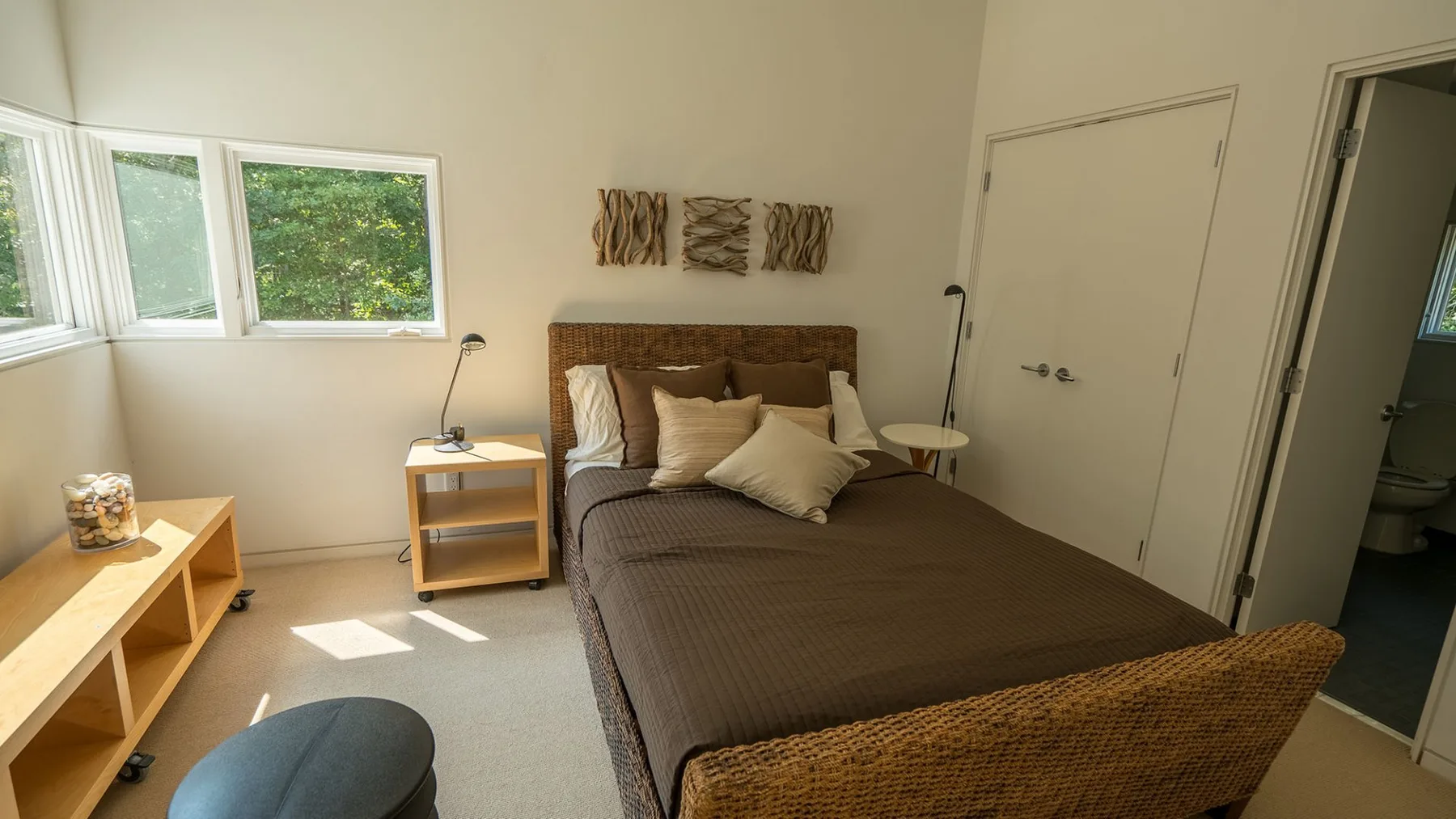 A bedroom with a bed, bedside tables, and windows along one wall.