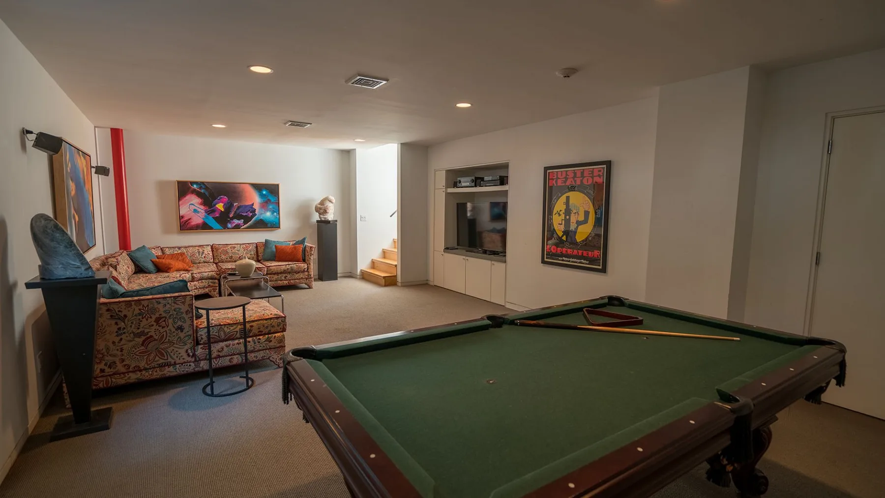 A game room features a green-felt pool table and colorful seating.