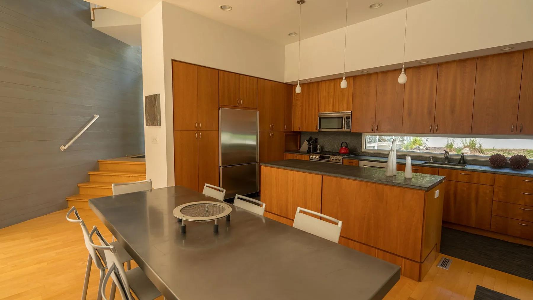 A kitchen with a dining table and a central island beneath wooden cabinets.