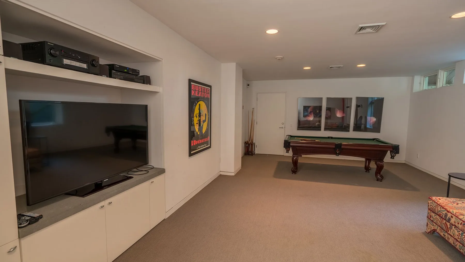 A basement recreation room with a television and a pool table.