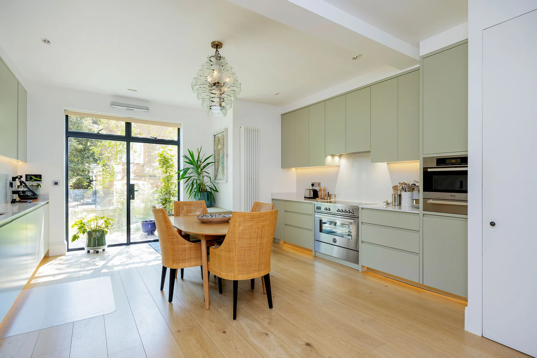 A bright kitchen and dining area with pale cabinetry and a wooden table.
