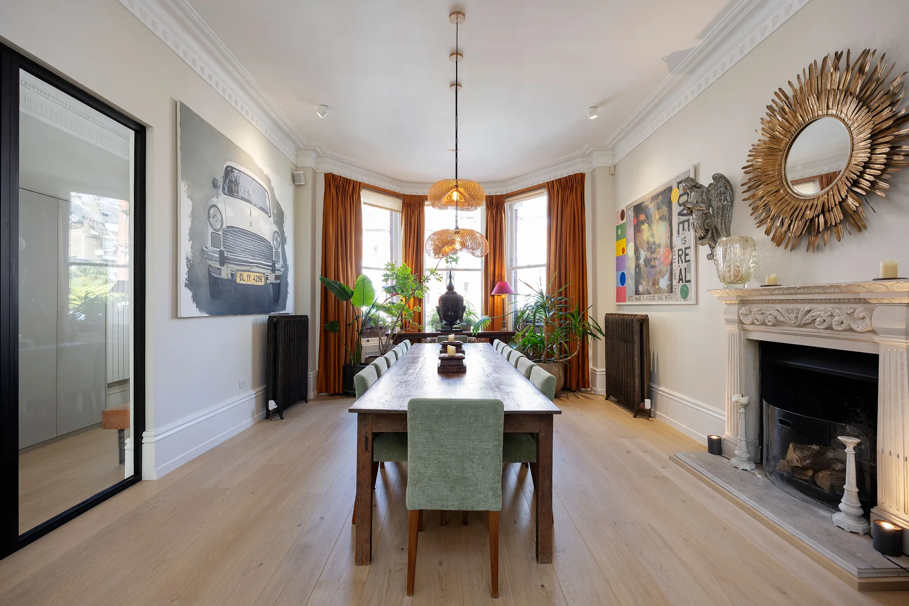 A bright dining room with a long table, large windows, and a fireplace.