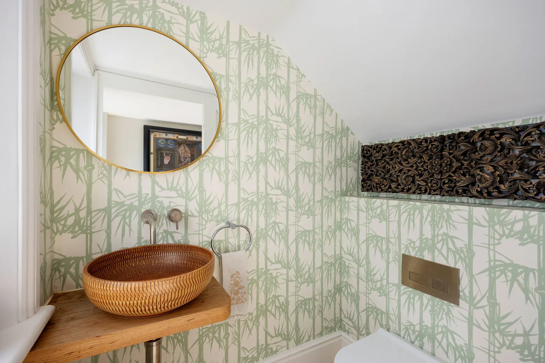 A bathroom vanity with a round mirror and a woven basin.