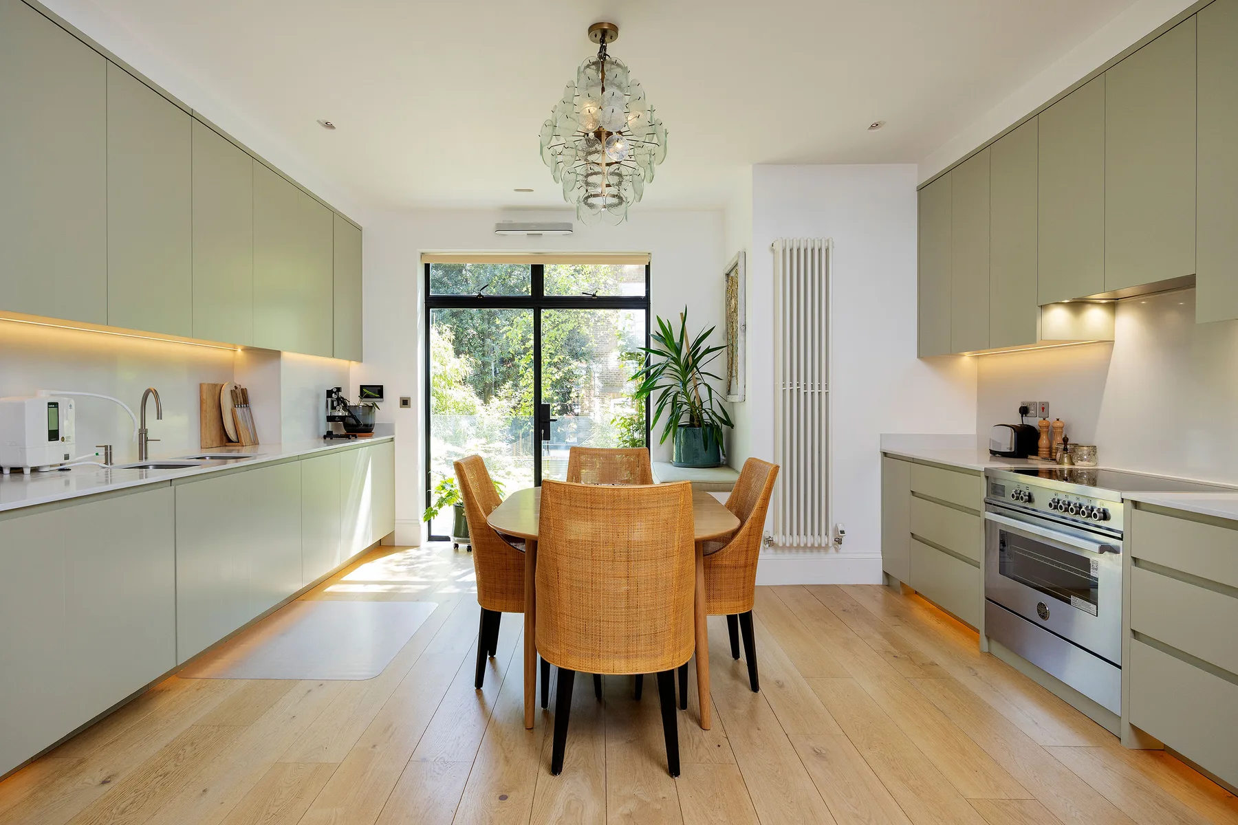 A modern kitchen with a wooden dining table and large glass doors.