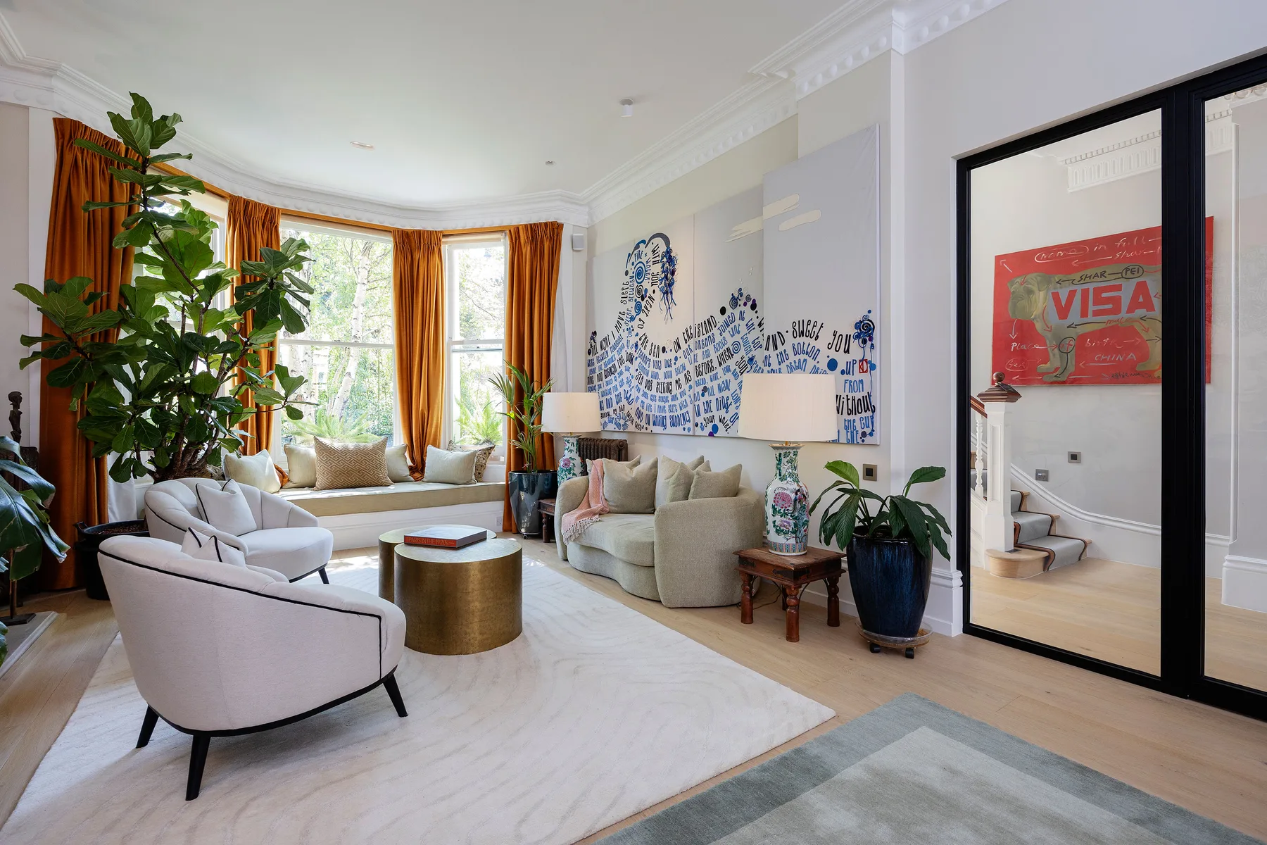 A bright living room with seating, large windows, and orange curtains.