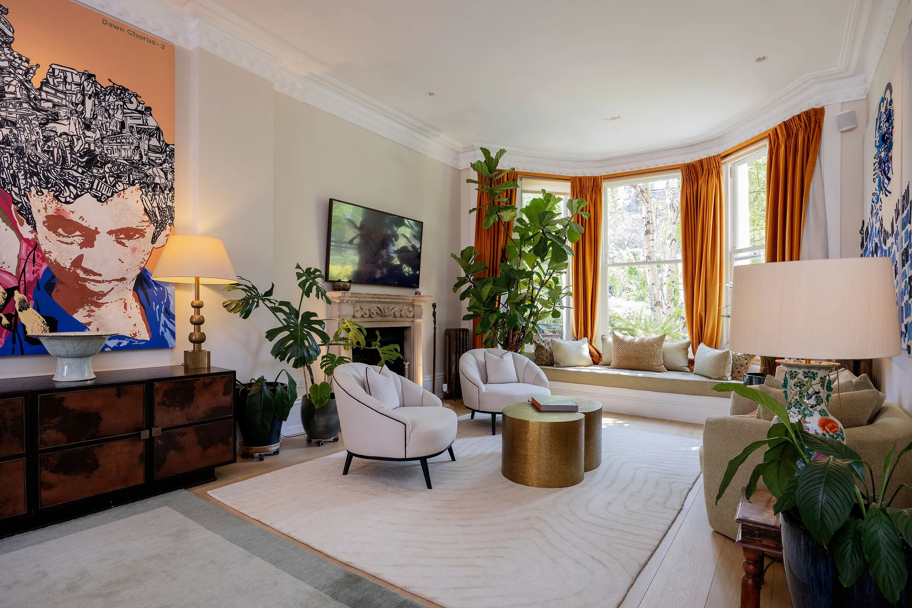 A bright living room with seating, a coffee table, and tall windows framed by orange curtains.