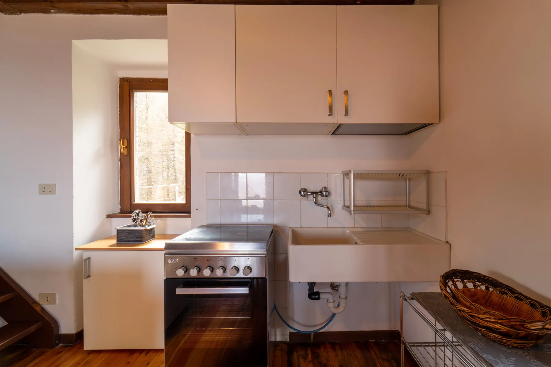 Una cocina compacta con estufa, fregadero y armarios de pared.