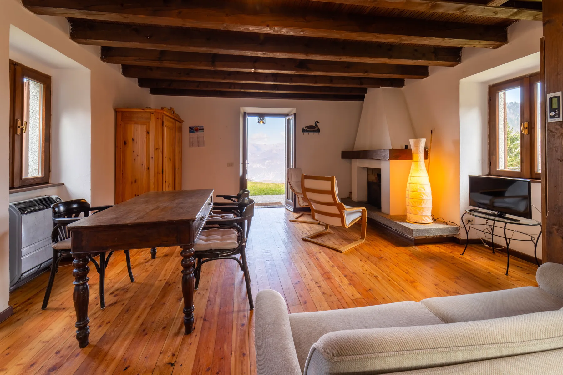 Una sala de estar y comedor rústica con vigas de madera y una chimenea.