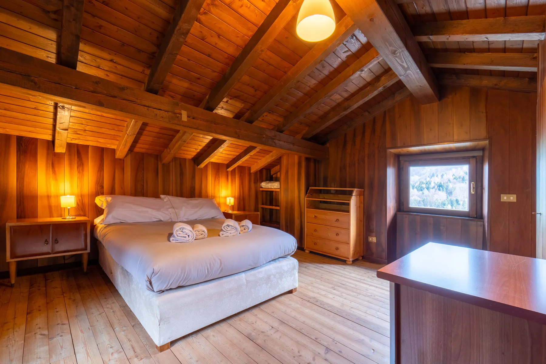 Un dormitorio con paredes de madera, una cama y un techo inclinado de madera.