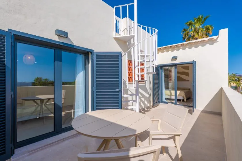 Una terraza soleada con puertas corredizas de vidrio y una mesa redonda al aire libre.