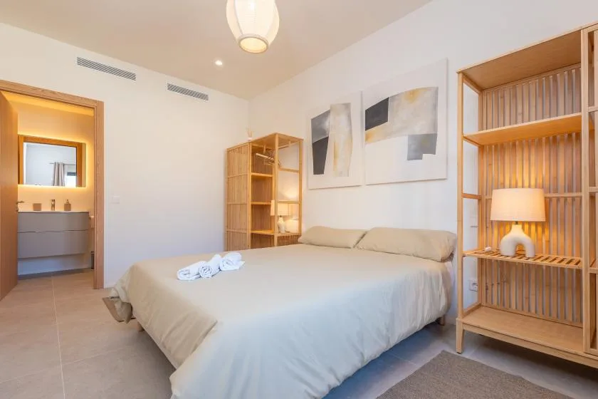 Un dormitorio luminoso con una cama hecha y arte abstracto en la pared.