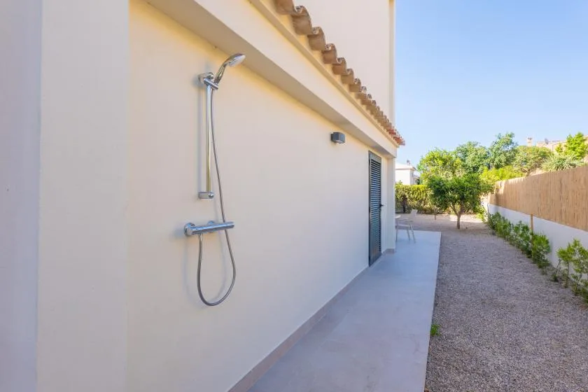Una zona de ducha exterior junto a un camino pavimentado y un jardín de grava.