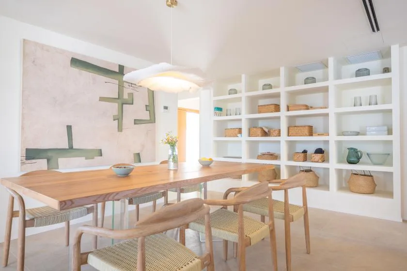 Un comedor luminoso con una mesa de madera, asientos y estantes empotrados.