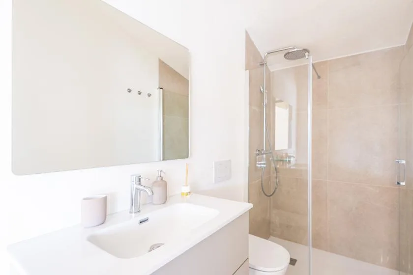 Un baño luminoso con lavabo y ducha de mampara de vidrio.