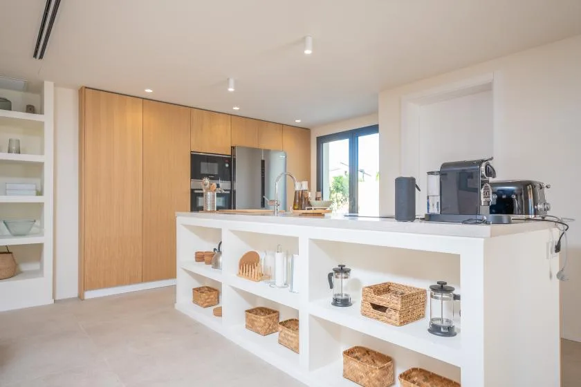 Una cocina luminosa con una isla blanca y armarios de madera.