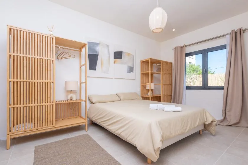 Un dormitorio luminoso con una cama, estanterías de madera y una ventana.