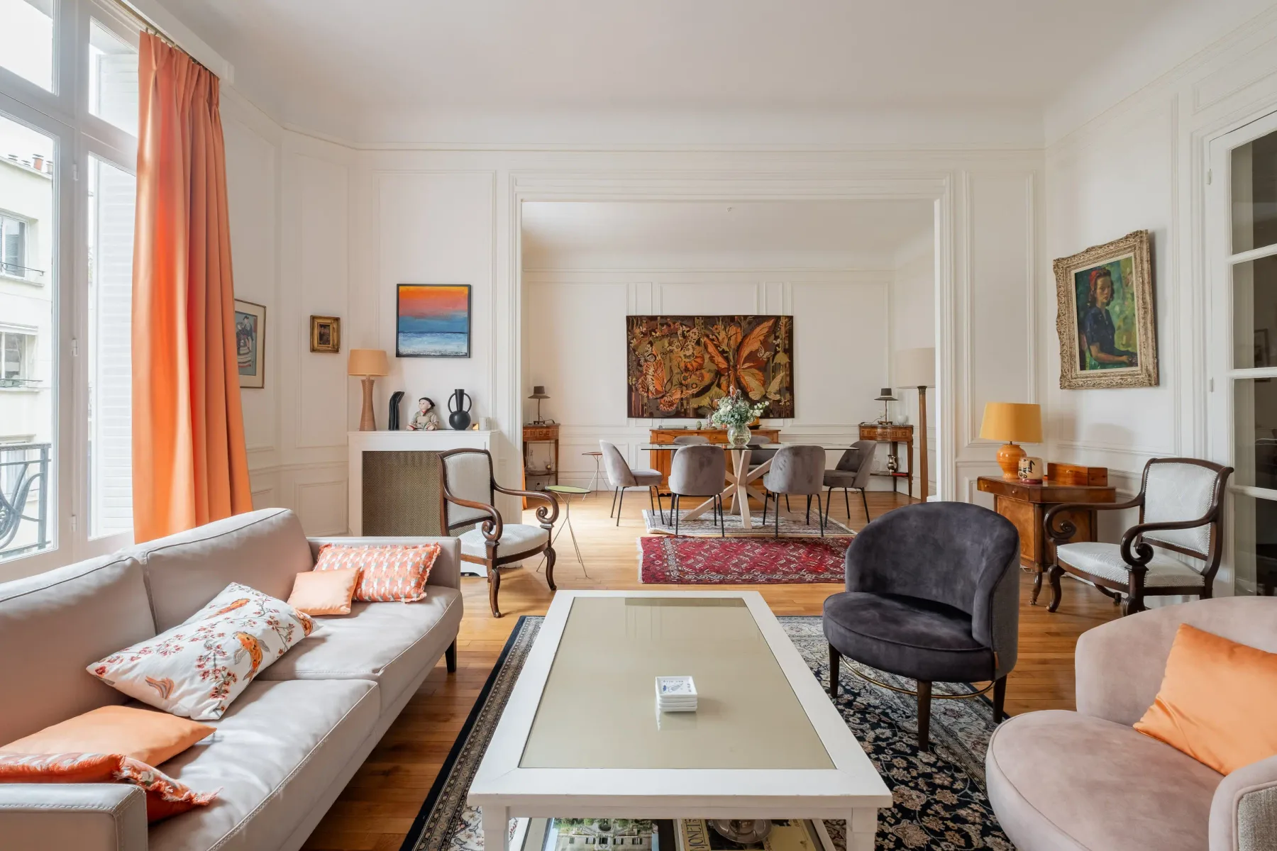 A bright living room with seating, a coffee table, and a dining area.