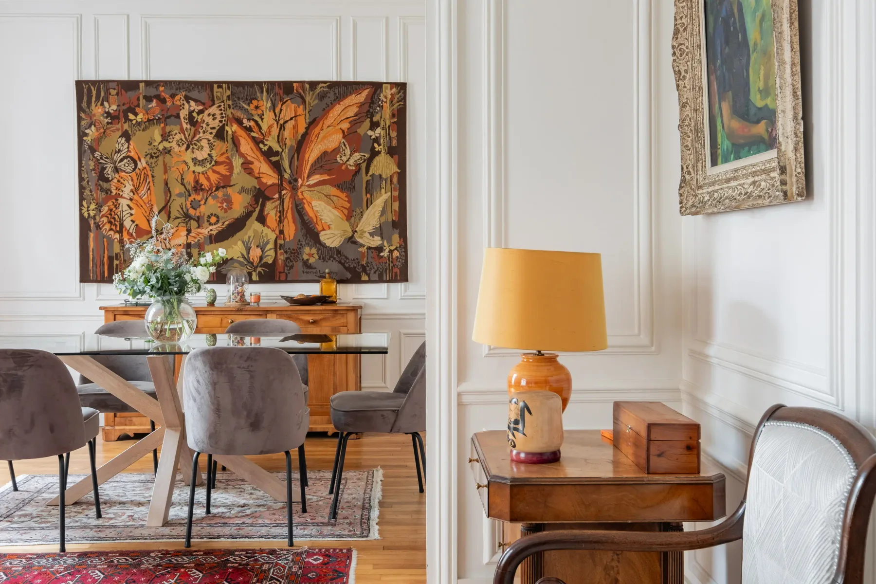 A dining area with a wooden table beneath a large butterfly artwork.