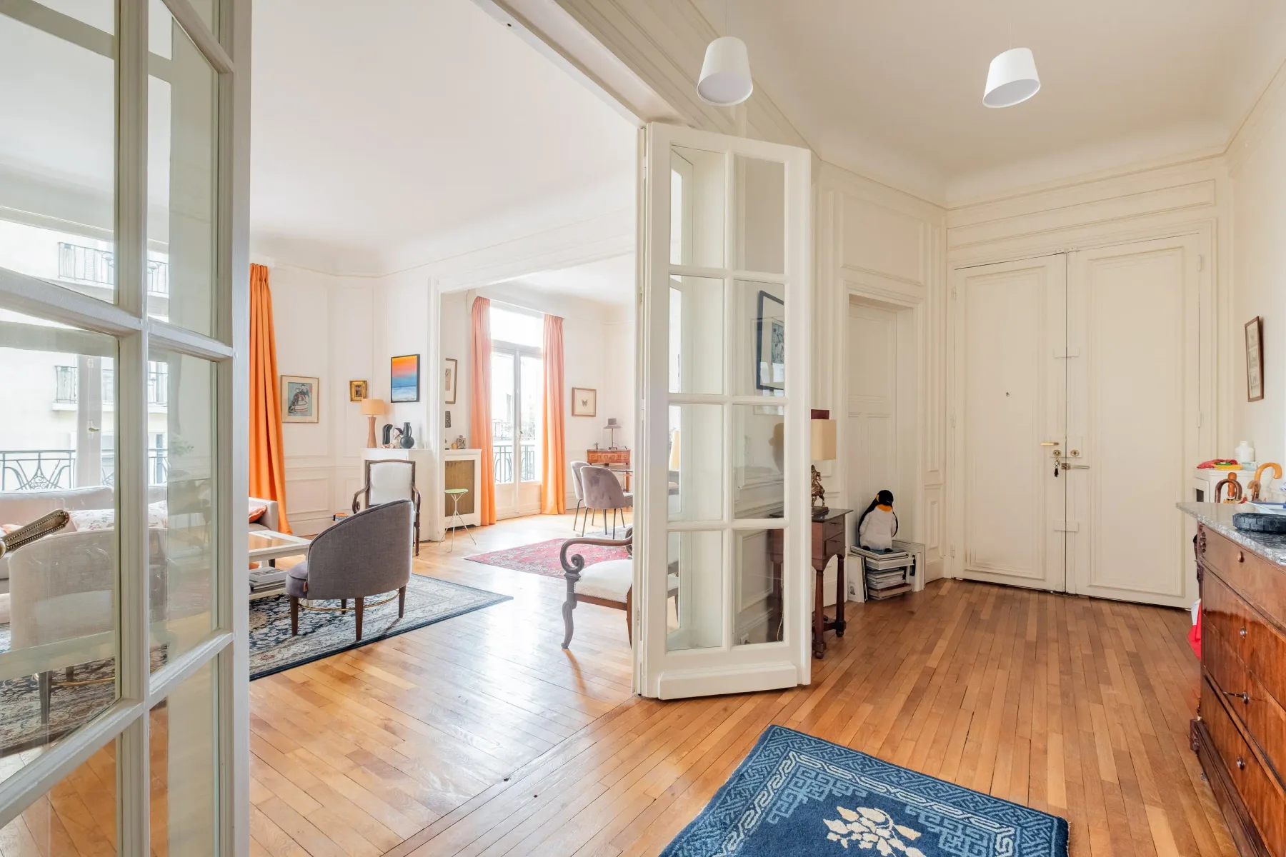 Bright interior with wooden floors, a glass partition, and a sitting area.