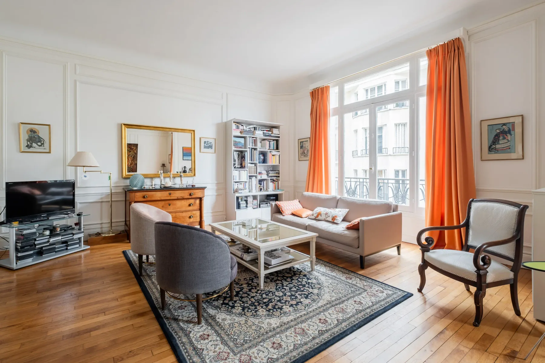 A bright living room with seating around a coffee table and tall windows.