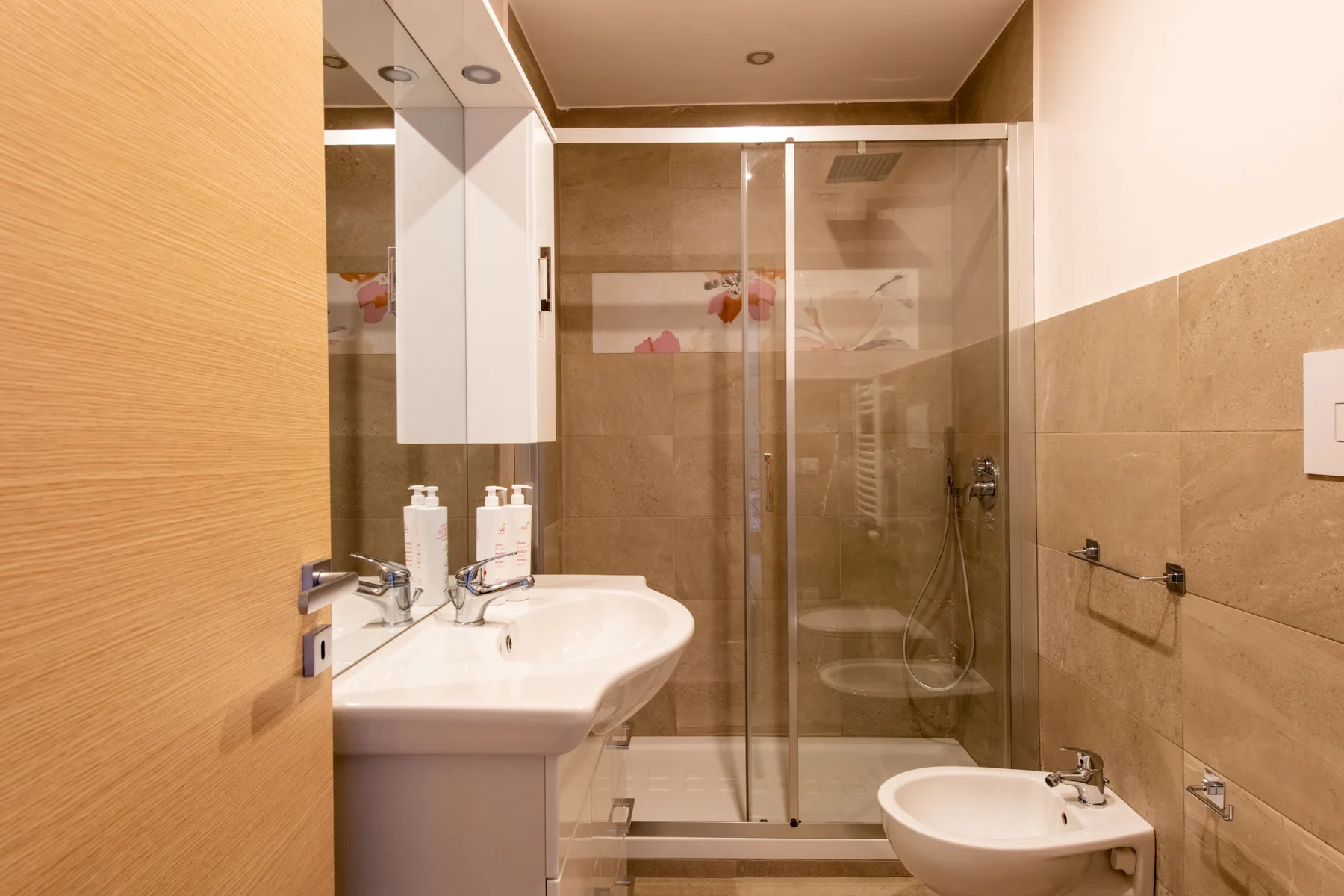 Un baño con lavabo y ducha con mampara de vidrio.