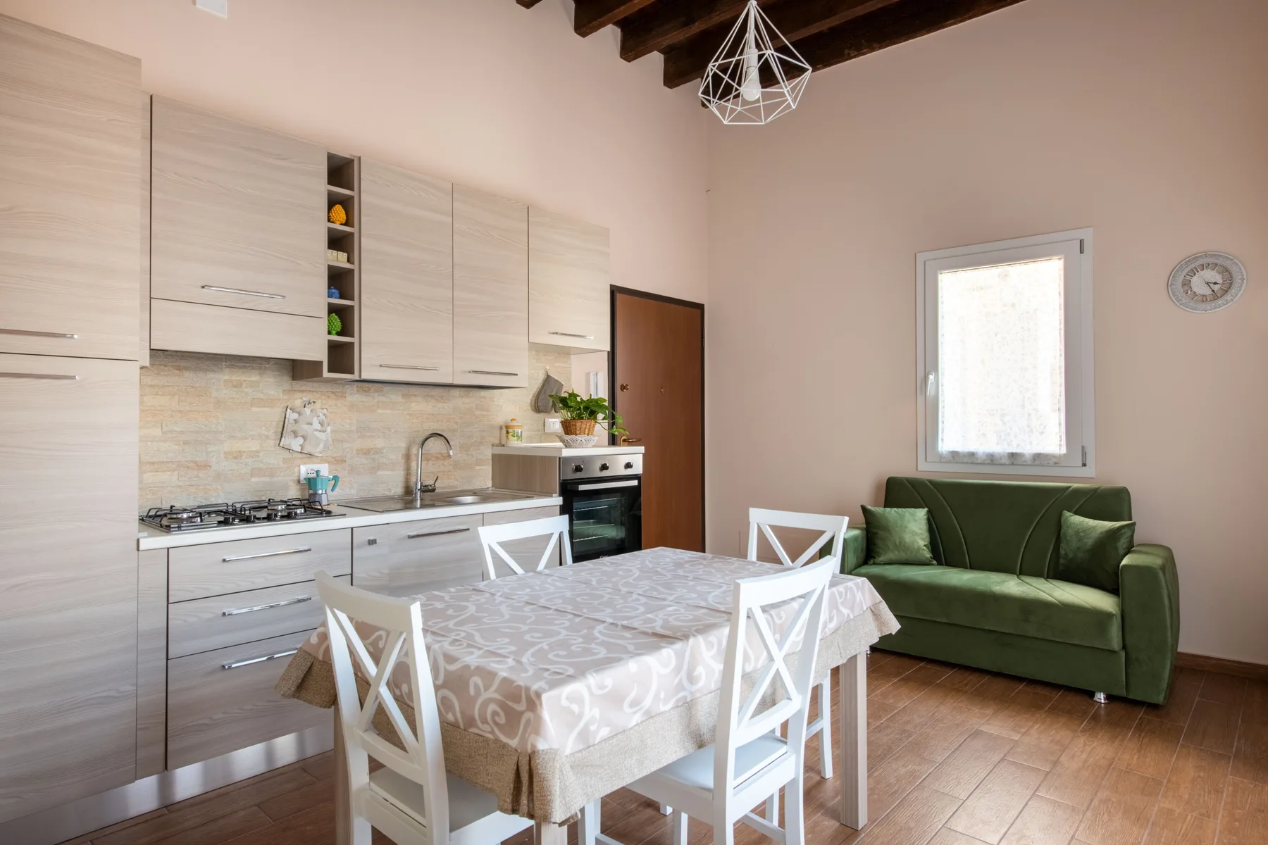 Una cocina y comedor con una mesa junto a un sofá verde.